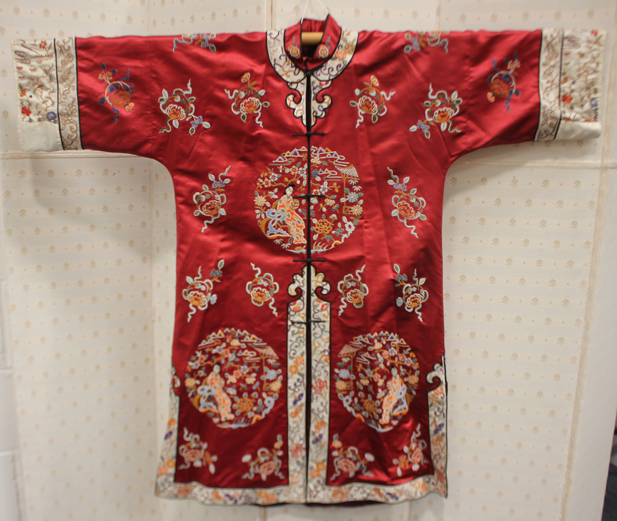 A Chinese red silk embroidered coat/robe, 20th century, worked in coloured threads with figure and