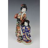 A Japanese Kutani porcelain figure group of a mother and child, Meiji period, each modelled standing