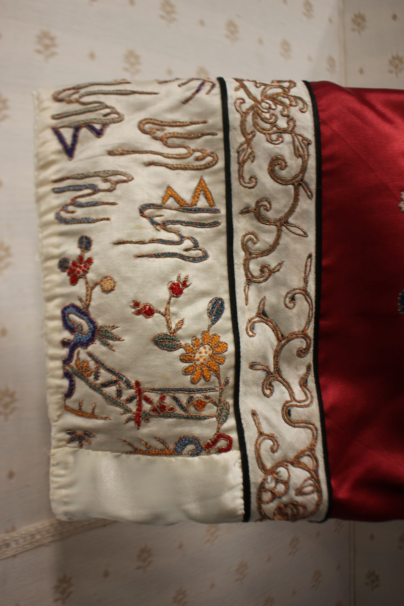 A Chinese red silk embroidered coat/robe, 20th century, worked in coloured threads with figure and - Image 5 of 19
