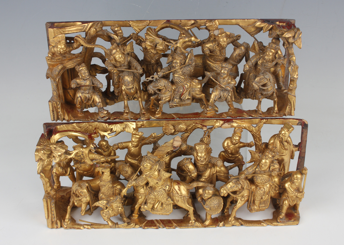 A pair of Chinese carved and pierced giltwood panels, early 20th century, each depicting battle