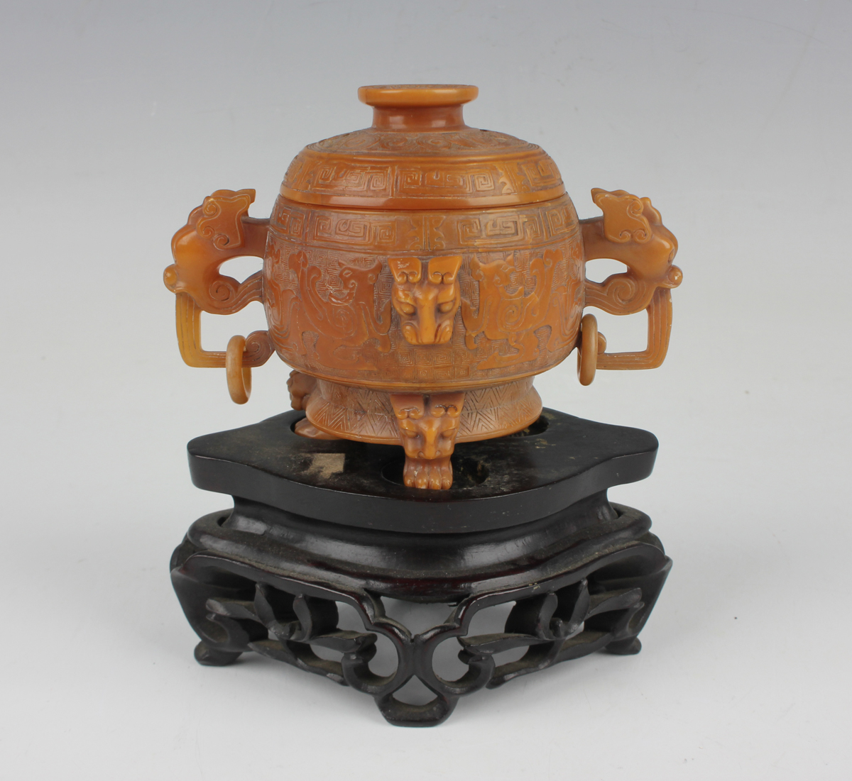 A Chinese archaistic butterscotch coloured soapstone tripod censer and cover, late Qing dynasty, the