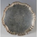 A George V silver circular card salver, presentation engraved, on scroll legs terminating in hoof