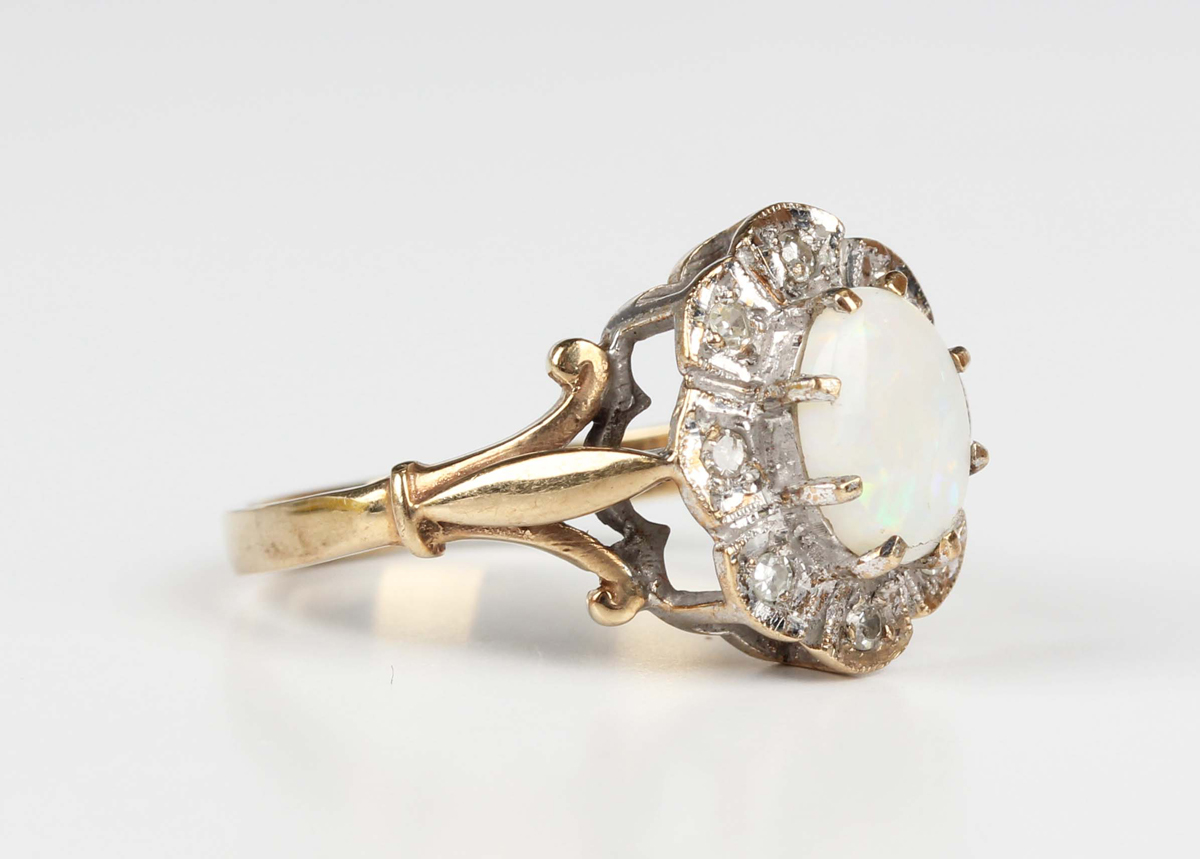 A 9ct gold, opal and diamond shaped oval cluster ring, claw set with the oval opal within a surround