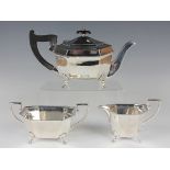 A George V silver three-piece tea set of rectangular canted corner form, raised on scroll legs,