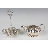 A George IV silver cream jug of squat circular lobed form with reeded rim, flanked by a foliate