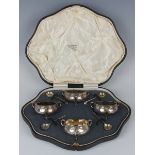 A set of four Edwardian silver circular salts, each hammered body with three foliate shouldered