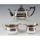 A George VI silver three-piece tea set of cushion form with gadrooned rims, raised on ball feet,