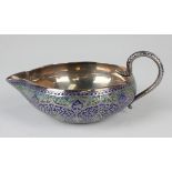 An Indian silver and enamelled jug of compressed circular form, the exterior chased with a design of