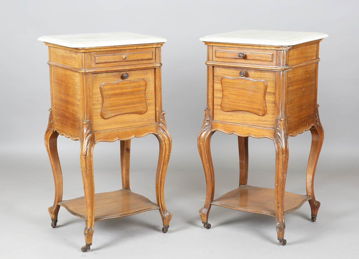 A pair of early 20th century French mahogany and white marble-topped beside cabinets, each fitted