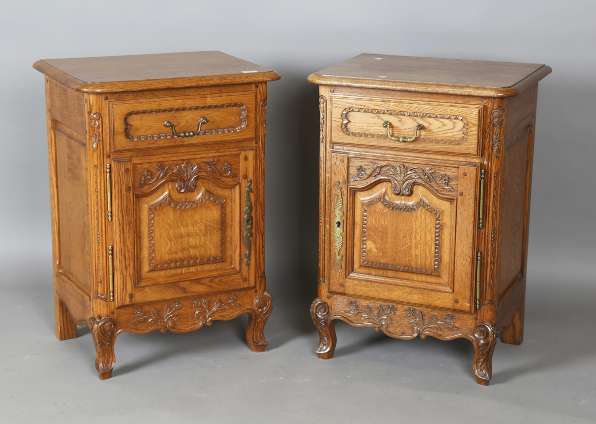 A pair of late 20th century French oak bedside cabinets, each fitted with a finely carved drawer and