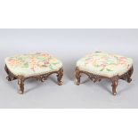 A pair of late Victorian walnut footstools, each with a needlework top, on carved legs, height 16cm,