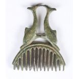 A Roman patinated bronze comb, the twin dolphin handle supporting an arched arrangement of teeth,