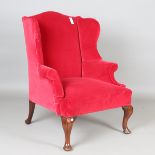 An early 20th century George I style wing back scroll armchair, upholstered in claret velour, on