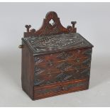 A 19th century oak candle box with carved decoration, the hinged sloping lid above a drawer,