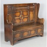 A mid-20th century Jacobean Revival oak box seat settle with panelled back and wing sides, height