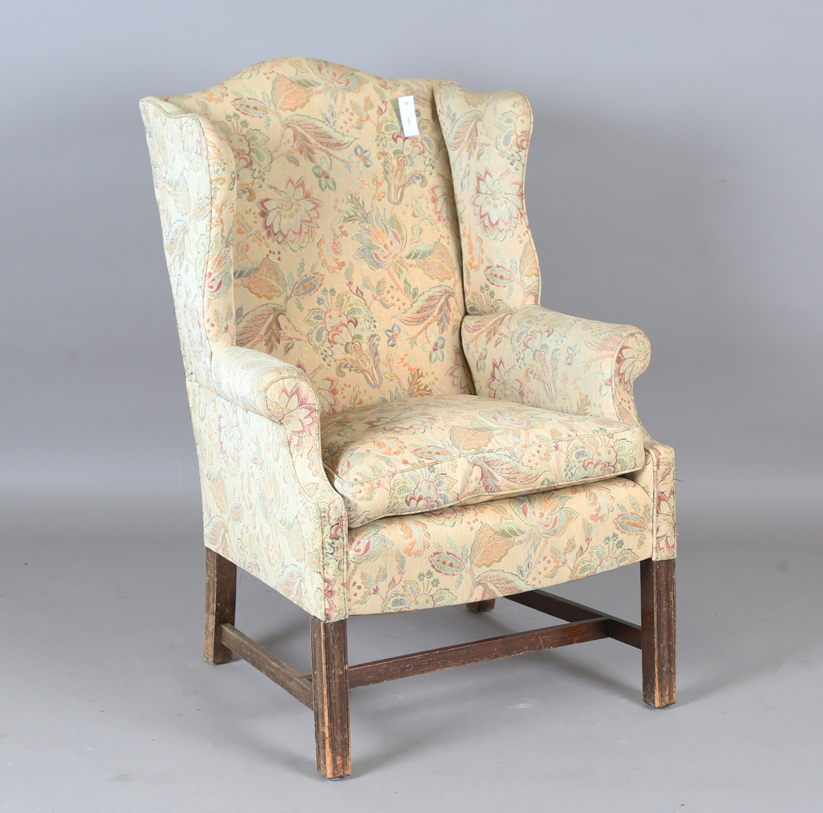 A 20th century George III style wingback armchair, upholstered in foliate machined tapestry style