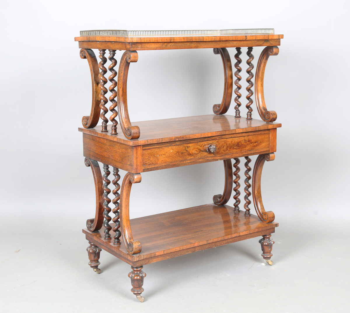 A mid-Victorian rosewood three-tier whatnot, fitted with a brass three-quarter gallery and a drawer,