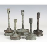 A group of five 16th century patinated metal socket candlestick shafts with later-made wooden bases,