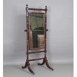 A small Regency mahogany cheval mirror with turned supports, raised on sabre legs and castors,