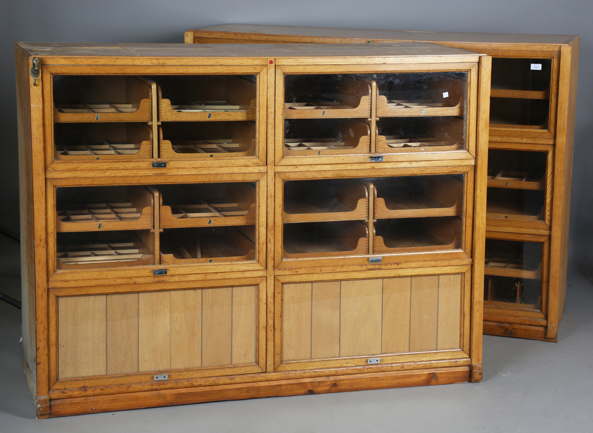 A pair of mid-20th century oak haberdashery cabinets, each fitted with six glazed doors enclosing