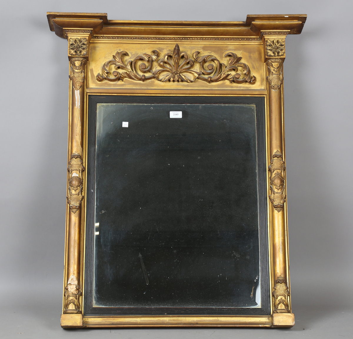 An early 19th century giltwood pier mirror with a carved foliate frieze and foliate cartouche-