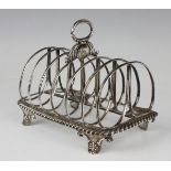 A George IV silver six-division toast rack with central foliate decorated loop handle, on a