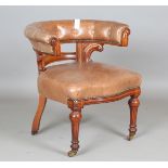 A Victorian mahogany library armchair, upholstered in brown leather, the curved back and shaped seat