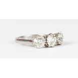 An 18ct white gold and diamond three stone ring, claw set with a row of old mine cut diamonds,