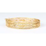 A gold filigree oval hinged bangle, indistinct mark, weight 14g, inside width 6.5cm.Buyer’s