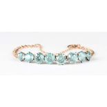 A gold and blue zircon bracelet, claw set with a row of eight graduated circular cut blue zircons,