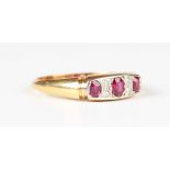 A gold and platinum, ruby and diamond ring, mounted with three oval cut rubies alternating with