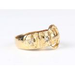 An 18ct gold and diamond ring in a buckle and strap design, mounted with two variously cut diamonds,