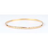 A gold circular bangle with facet cut decoration, unmarked, weight 6.2g, inside diameter 5.9cm.