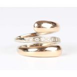 A two colour gold and colourless gem set ring in a spiral design, mounted with a row of circular cut