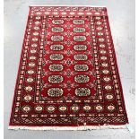 A Pakistan bokhara rug, modern, the claret field with two columns of guls, within a sunburst gul