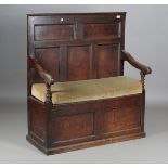 An 18th century provincial oak box seat settle, the fielded panel back above open arms and a