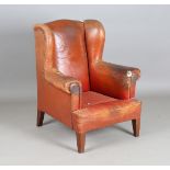 An early 20th century brown leather wing back armchair, height 100cm, width 83cm, depth 75cm (