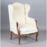 An early 20th century French walnut wingback armchair, raised on carved cabriole legs, height 110cm,