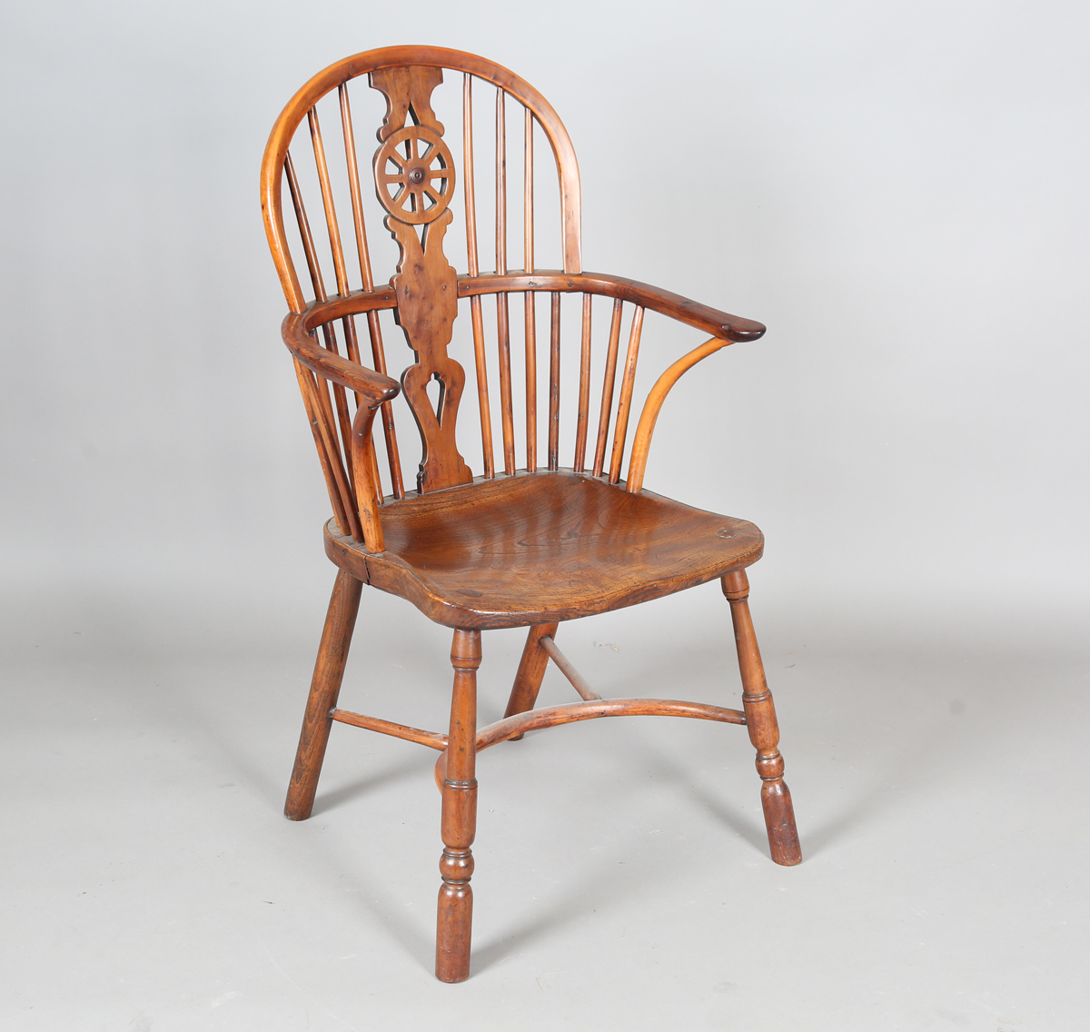 An early Victorian yew and elm stick and wheel back Windsor armchair with shaped panel seat and