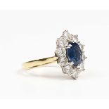 An 18ct gold, sapphire and diamond cluster ring, claw set with oval cut sapphire within a surround