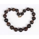 A single row necklace of graduated spherical banded agate beads on a screw down base metal clasp,