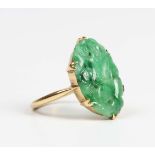 A gold and jade ring, the oval jade panel carved with a bird and foliate motifs, detailed '18ct',