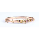 An Edwardian gold, amethyst and seed pearl oval hinged bangle, the front collet set with three