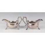 A pair of George V silver sauceboats, each with a gadrooned rim and scroll handle, raised on scallop