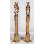 A pair of 17th century oak architectural columns, each surmounted by a carved oak figure depicting