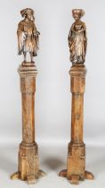 A pair of 17th century oak architectural columns, each surmounted by a carved oak figure depicting