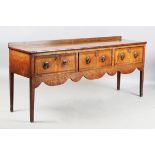 A George III provincial oak dresser base, the crossbanded top above three drawers and a shaped