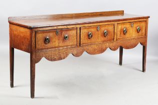 A George III provincial oak dresser base, the crossbanded top above three drawers and a shaped