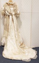 An early 20th century cream silk wedding dress with net and pearl appliqué borders and long train,