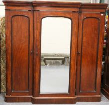 A Victorian mahogany breakfront wardrobe, fitted with a central mirrored door enclosing trays and